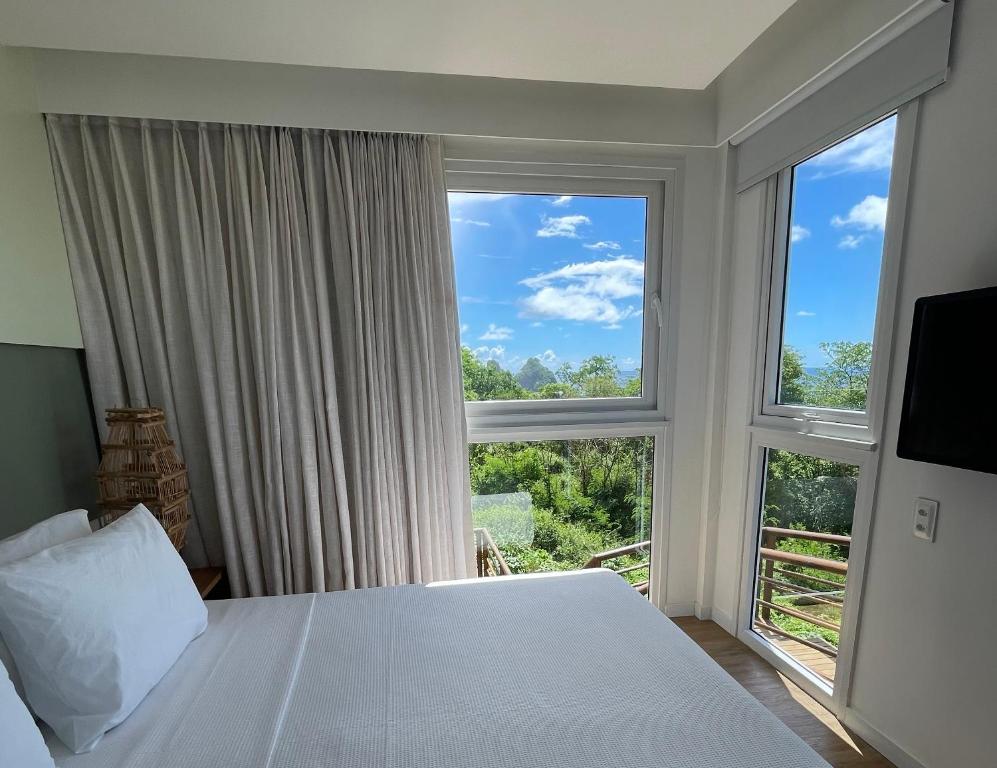 a bedroom with a bed and two large windows at Pousada Mar em Mim in Fernando de Noronha
