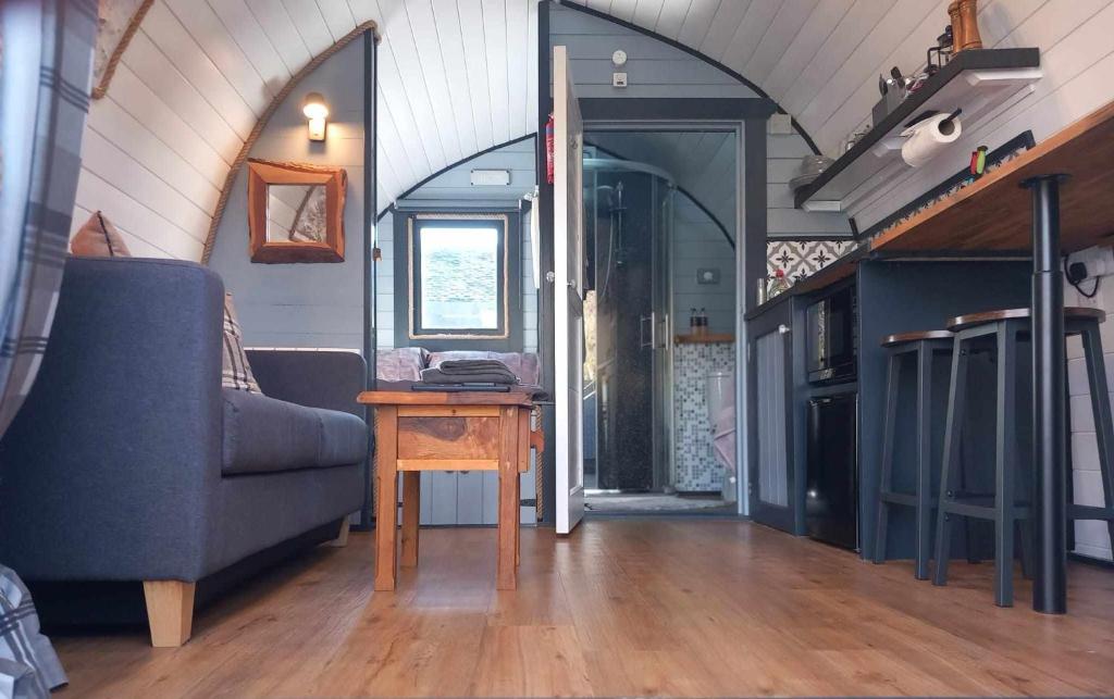 a living room with a blue couch and a table at Etive Pod, West Highland Way Holidays in Kinlochleven