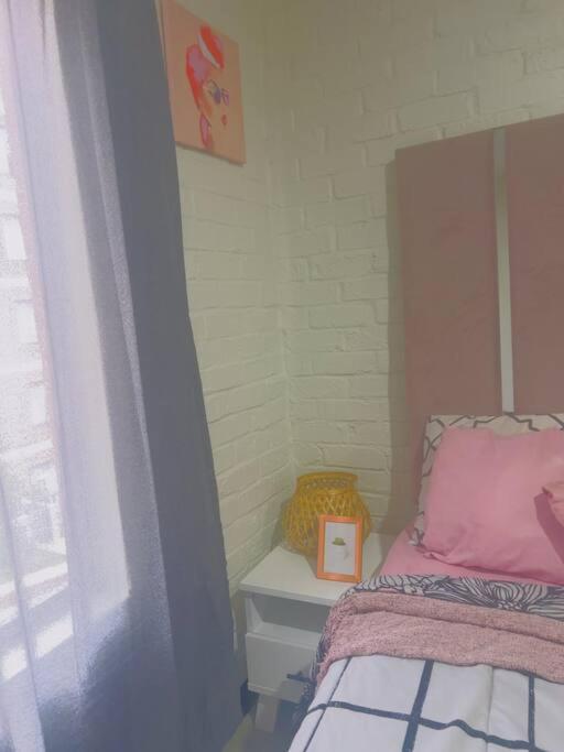 1 dormitorio con 1 cama y 1 mesa con reloj en Stylish apartment in Maboneng, en Johannesburgo