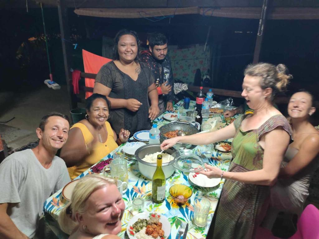 un gruppo di persone seduti intorno a un tavolo di Tapuhere Homestay Room a Fare (Huahine Nui)