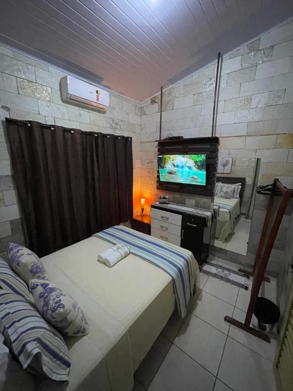 een kleine slaapkamer met een bed en een televisie bij Casa de Pedra in Pirenópolis