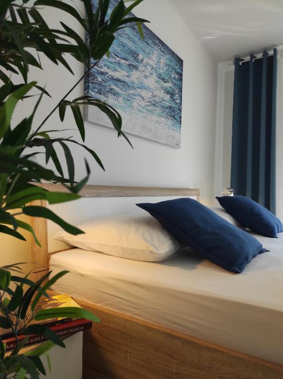 una camera da letto con un letto con cuscini blu e una pianta di Punta Faro a Zara (Zadar)
