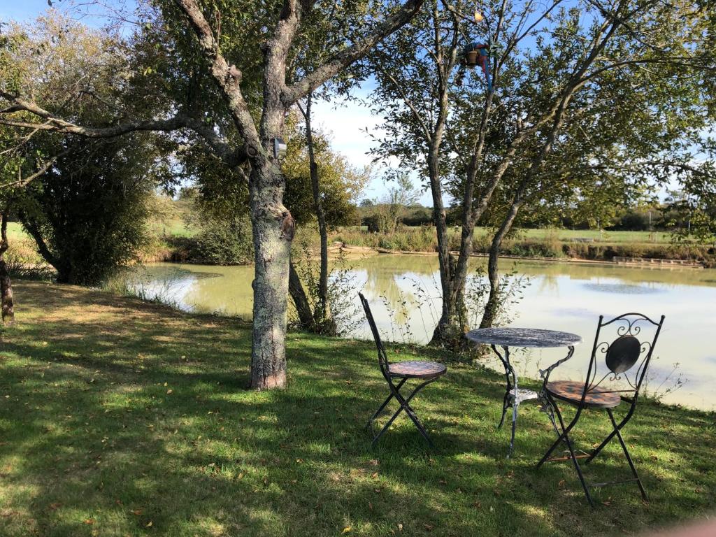 un tavolo da picnic con sedie di fronte a un lago di The Lake Room Cottage with Private Fishing Lake a Bommiers