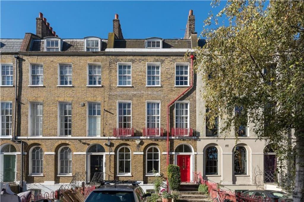 a large brick building with a red door at Entire Ground Floor Flat, Free Off-Street Parking and Large Garden in London