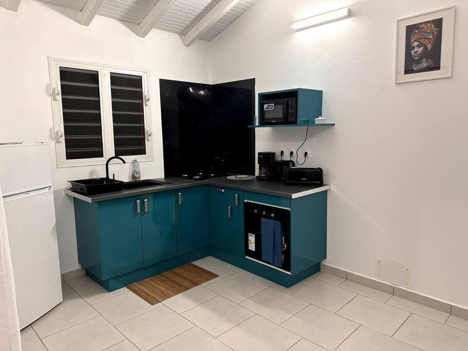 - une cuisine avec des placards bleus et un four micro-ondes dans l'établissement L'Écrin de Verdure, à Sainte-Anne