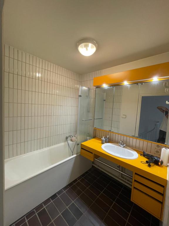 a bathroom with a sink and a mirror and a tub at Étage d’un duplex au 17ème arr de Paris , vue sur le Défense, à 10min des champs Élysée in Paris