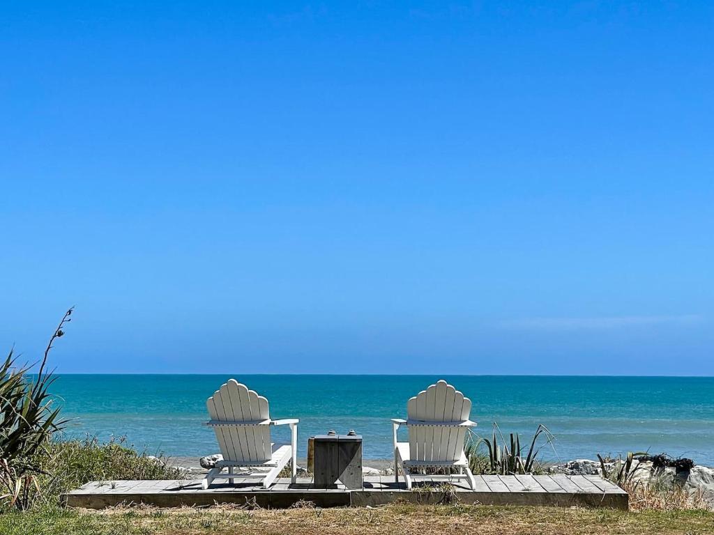 two chairs and a table on the beach at Beachfront Retreat On Revell in Hokitika