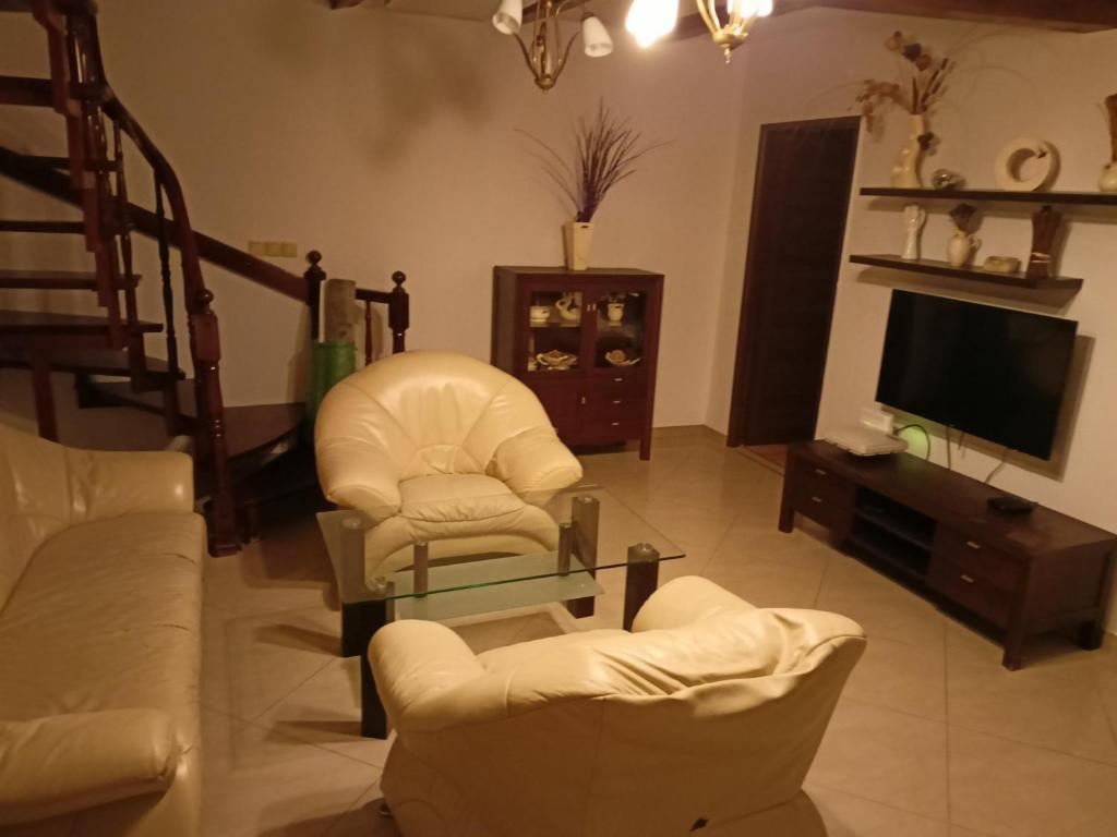 sala de estar con sillas blancas y TV en Domek na Odrzańskiej, en Moryń