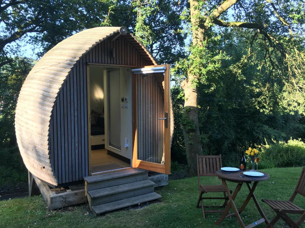 Cabaña de madera pequeña con porche y mesa en birdbox@glanrhyd, en Pontardawe