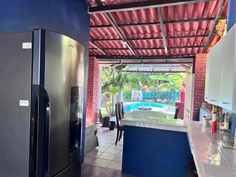 a kitchen with a stainless steel refrigerator and a pool at Casa en Condominios San Blas 5 minutos del Tunco in La Libertad