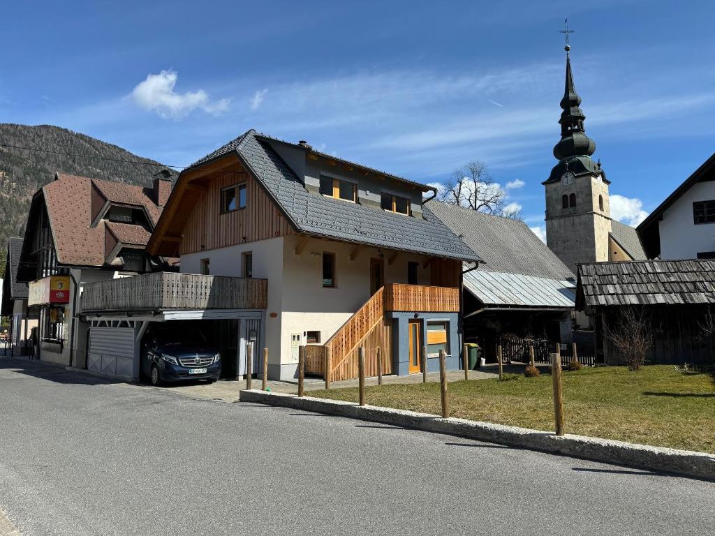 ein Haus an der Seite einer Straße mit einer Kirche in der Unterkunft Gloria Holiday - Kranjska Gora Apartments in Kranjska Gora