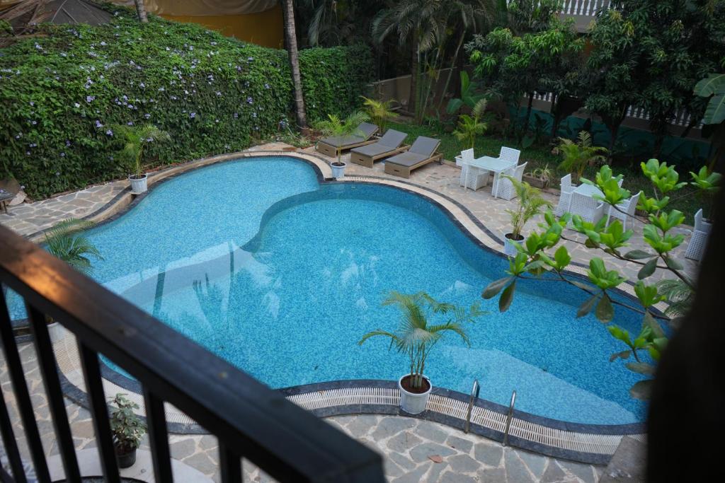 une grande piscine avec des chaises et un balcon dans l'établissement La Ritz beach luxury hotel, à Vieux-Goa
