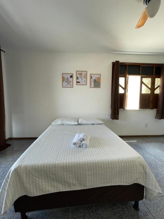 a bedroom with a bed with a white comforter at Pousada aconchegante in Jequié