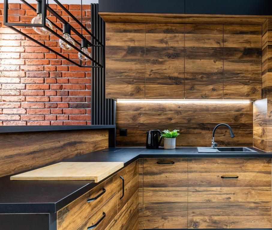 a kitchen with wooden cabinets and a brick wall at Loft Apart in Iława