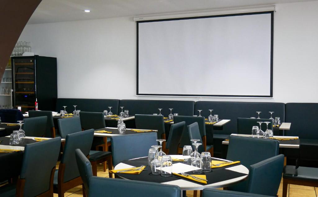 une salle à manger avec des tables, des chaises et un tableau blanc dans l'établissement LE CENTRAL HOTEL BAR RESTAURANT, à Balaruc-les-Bains
