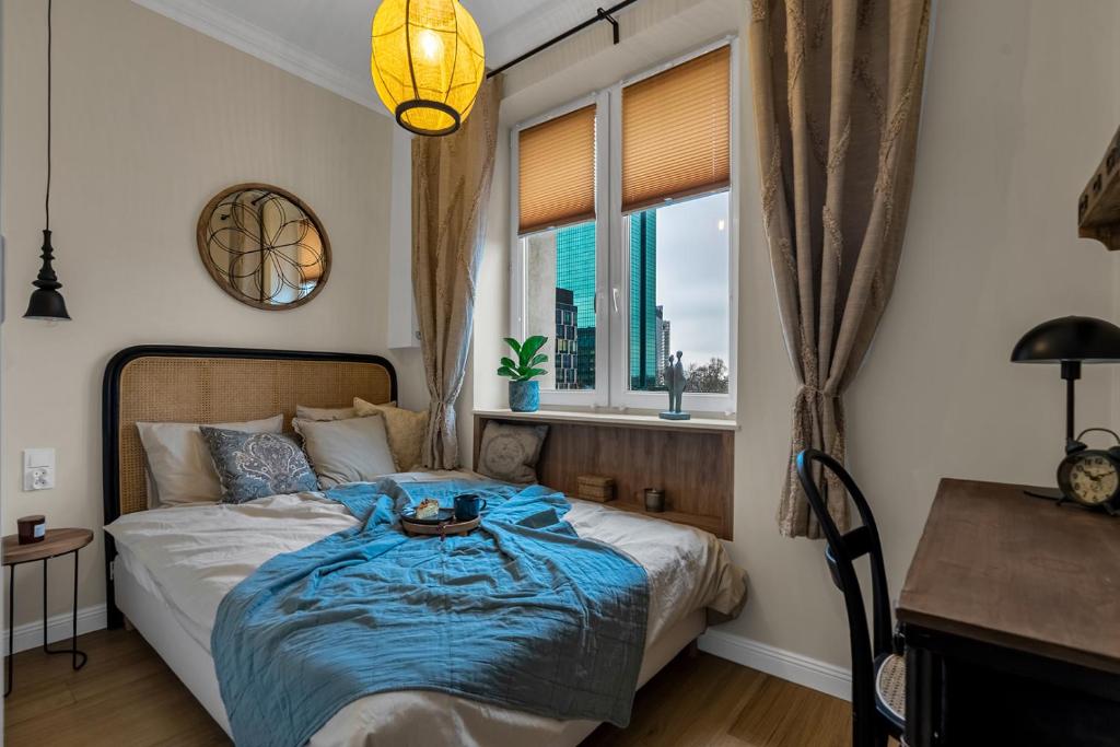 a bedroom with a bed with a blue blanket and a window at Warsaw New Town - Top Location, Park & Subway Nearby by Rentujemy in Warsaw