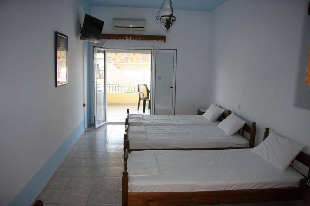 two beds in a room with a balcony at Koletsis Rooms (Villa Koletsis) in Ammoudia