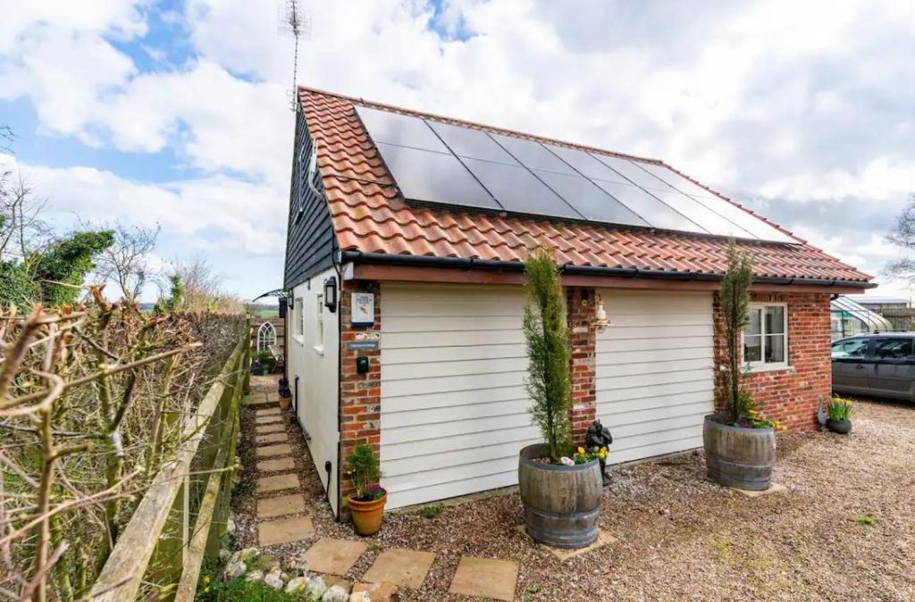 a small house with solar panels on the roof at Suffolk Fieldview Country Cottage in Toft Monks