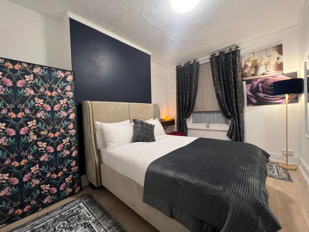 a bedroom with a large bed with a floral wall at Cambridge Heritage Apartments in Cambridge