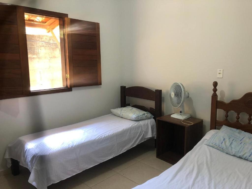 a bedroom with two beds and a fan and a window at Chácara Aconchego in Três Marias
