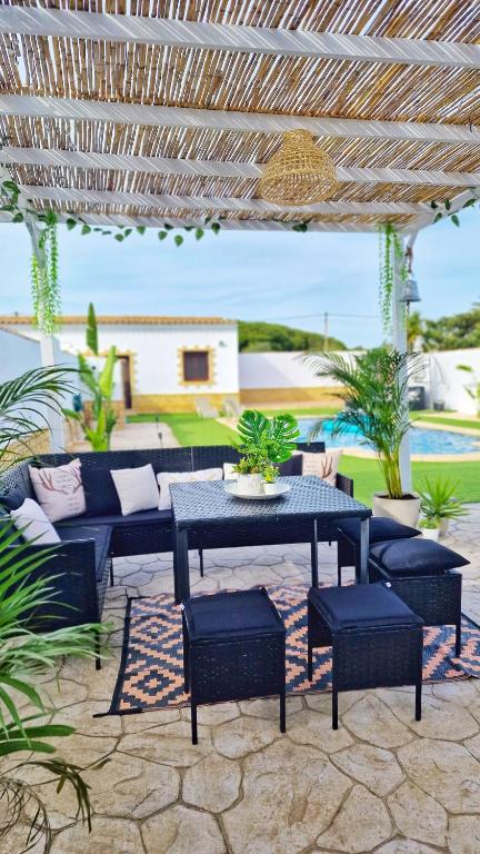 a patio with a table and chairs under a pergola at Villas Luins in Chiclana de la Frontera