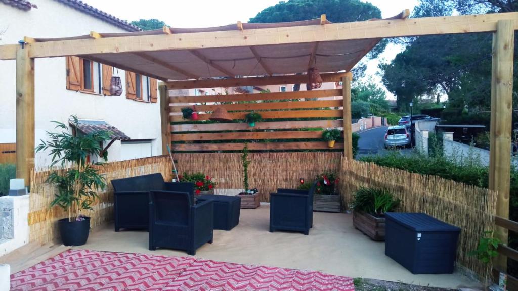 une terrasse avec une pergola en bois et des plantes dans l'établissement Appartement calme au jardin de Cesar, à Fréjus