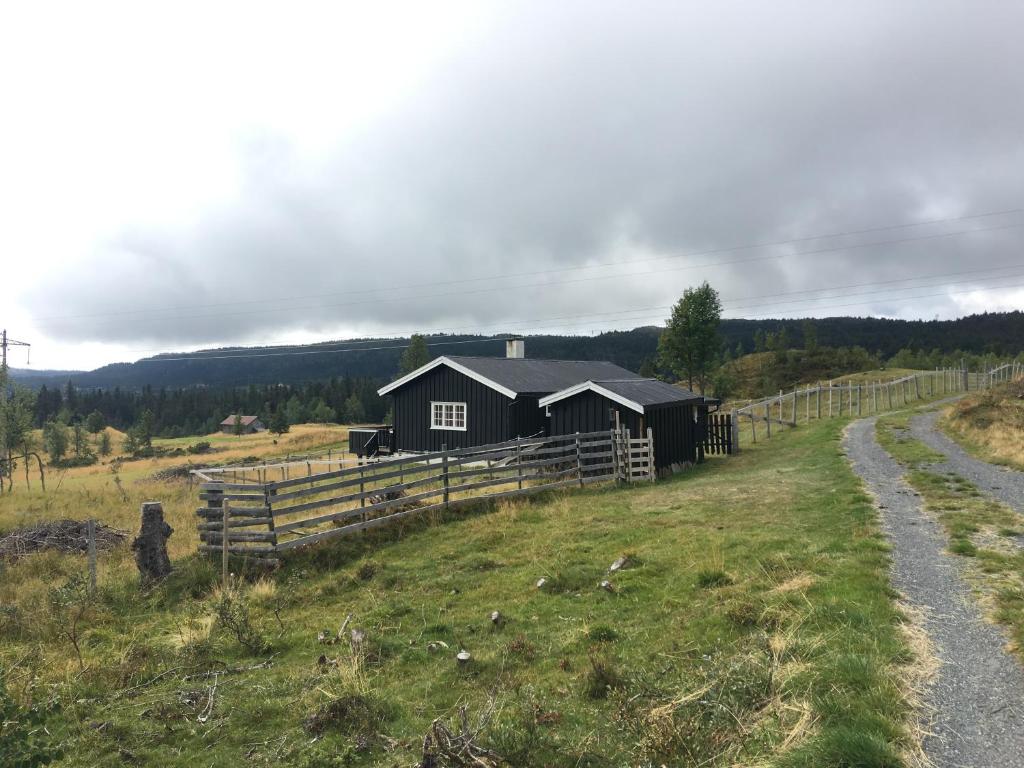 een zwarte schuur in een veld naast een hek bij Einkjerrbu cabin by Norgesbooking - in Svingvoll