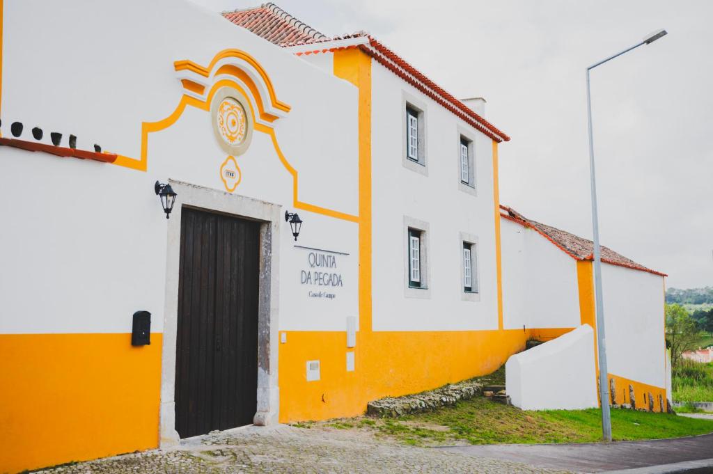 Casa de Campo da Quinta da Pegada في أوبيدوس: مبنى برتقالي وبيض مع باب
