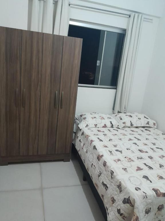 a bedroom with a bed and a wooden cabinet at Quarto próximo Av JK in Patos de Minas