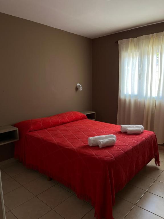 a bedroom with a red bed with two towels on it at Alquiler temporario zapala Amanecer in Zapala