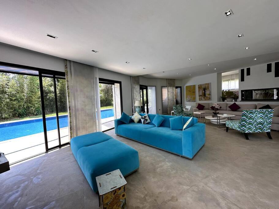 a living room with a blue couch and a pool at Villa Sérénité Cabo Negro in Bicas