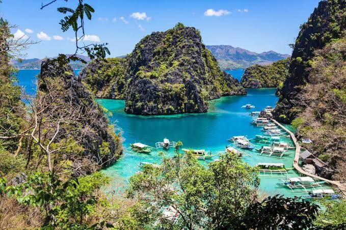 a group of boats in a bay with mountains at Room in Coron in Coron