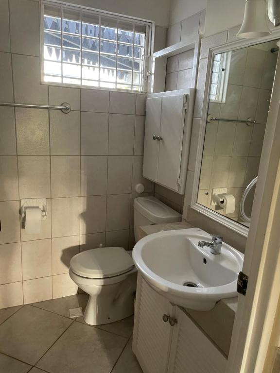 a white bathroom with a toilet and a sink at Studio apartment in heart of south coast Barbados in Bridgetown