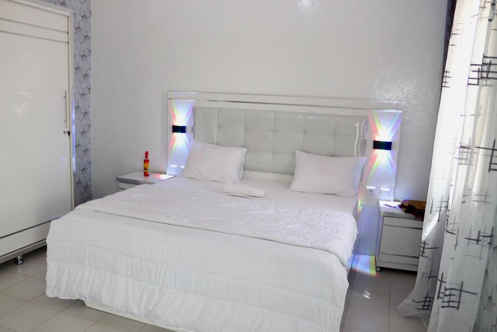a white bedroom with a white bed and two lamps at Bel appartement F2 Thies in Thiès