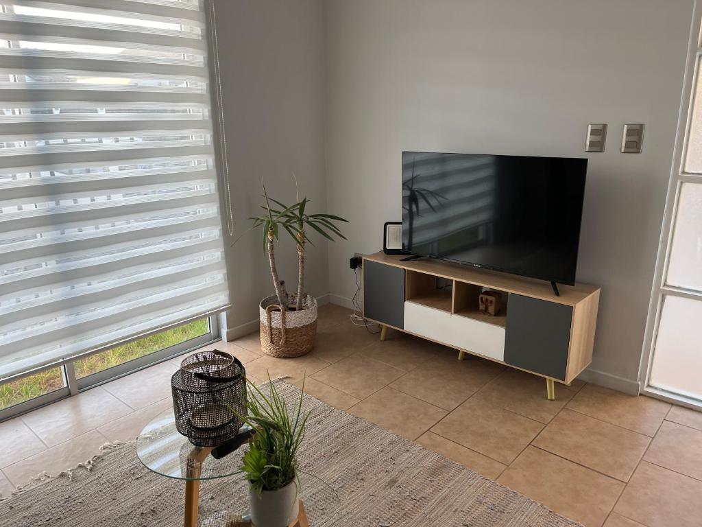 sala de estar con TV de pantalla plana en un soporte en Casa amoblada en sector residencial, en Vallenar