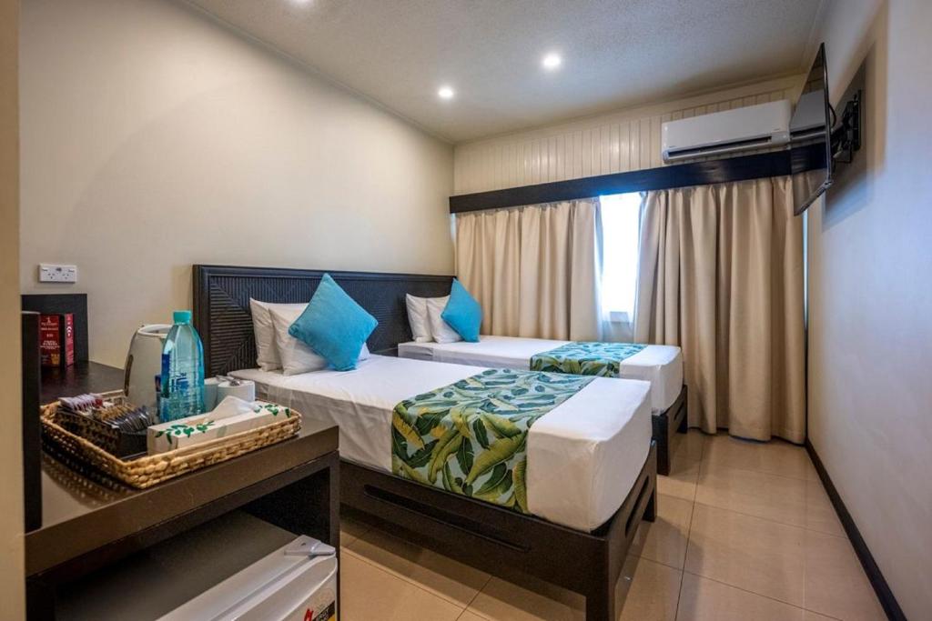 a hotel room with two beds and a window at Fiji Gateway Hotel in Nadi