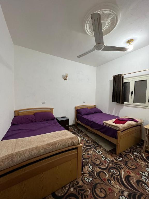1 dormitorio con 2 camas y ventilador de techo en Oasis Camp en Bawiti