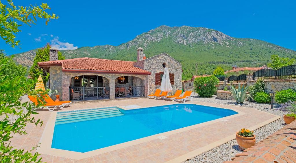 a house with a swimming pool in front of a mountain at Villa Serena in Fethiye