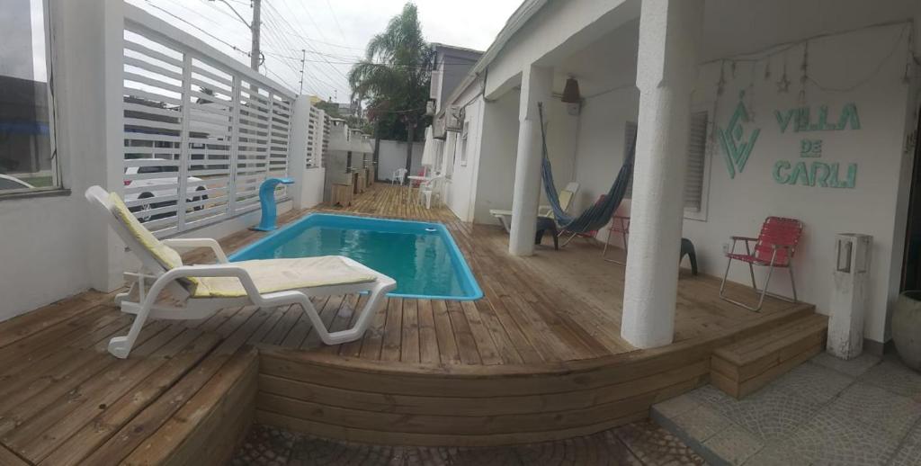 a small swimming pool on a wooden deck with a chair at Hotel Villa De Carli Beach in Rio Grande
