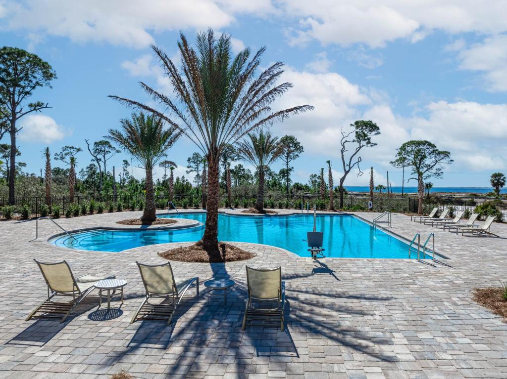 a pool with chairs and a palm tree at Minutes to Beach ,Golf Cart Included, Ocean View Pool ,Beach Equip, Ocean Therapy in Saint Joe Beach