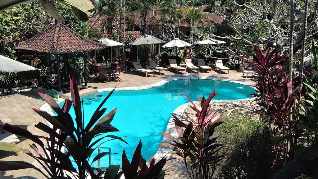 a swimming pool in a resort with chairs and umbrellas at Dasa Wana Resort in Candidasa
