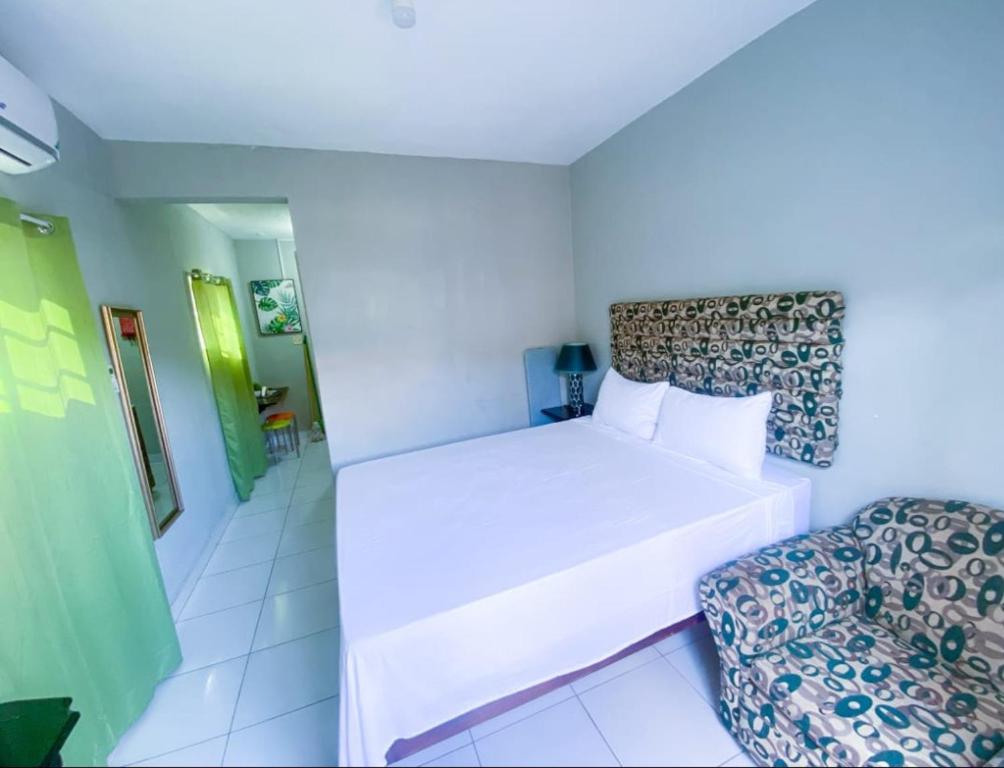 a white bedroom with a bed and a chair at Jobs Inn Jamaica in Montego Bay