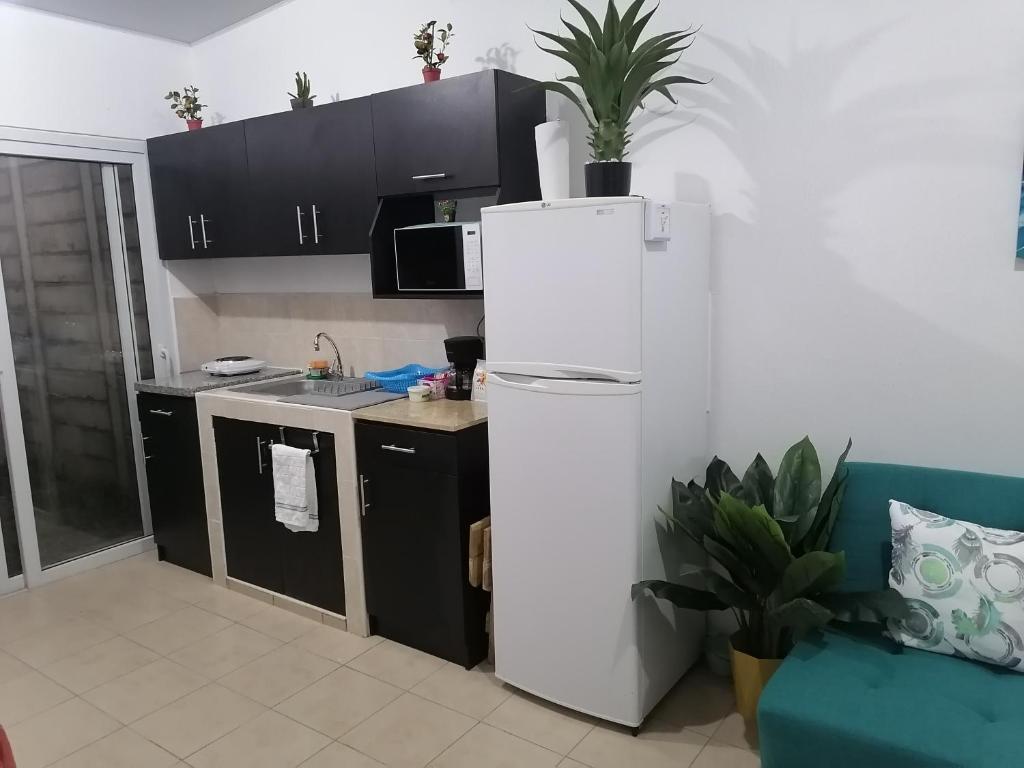 eine Küche mit einem weißen Kühlschrank und schwarzen Schränken in der Unterkunft Nenes Relax Home in Santa Ana