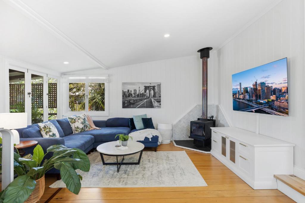 a living room with a blue couch and a fireplace at Tranquil 2-Bed Family Home with Deck Among Trees in Brisbane