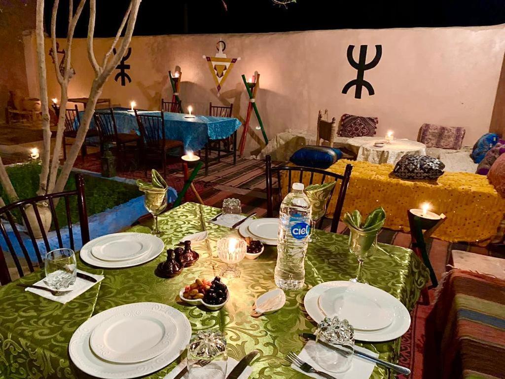 un tavolo con piatti e bicchieri e una bottiglia d'acqua di Riad Assia Foum Zguid a Foum Zguid