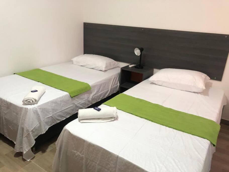 duas camas com lençóis verdes e brancos num quarto em Apartasuite 10-72. 2 em Santa Marta