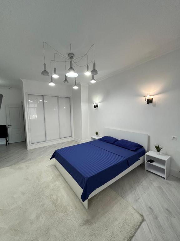 a bedroom with a blue bed in a white room at Уютная квартира на набережной! in Astana