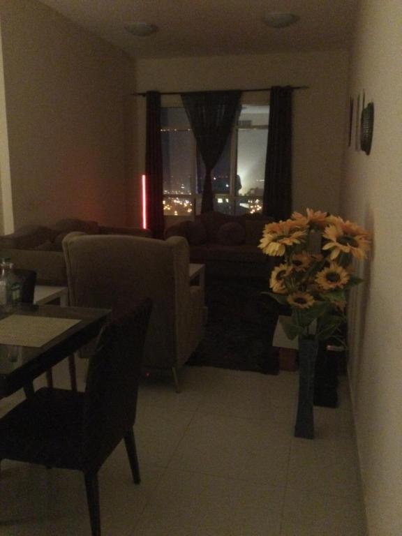 una sala de estar con sofá y un jarrón de flores en 1 bedroom apartment, en Fujairah