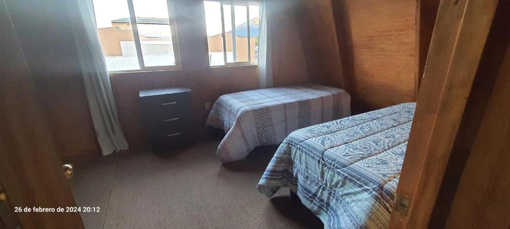 a small room with two beds and a window at Cabaña Fortunata in Puerto Williams