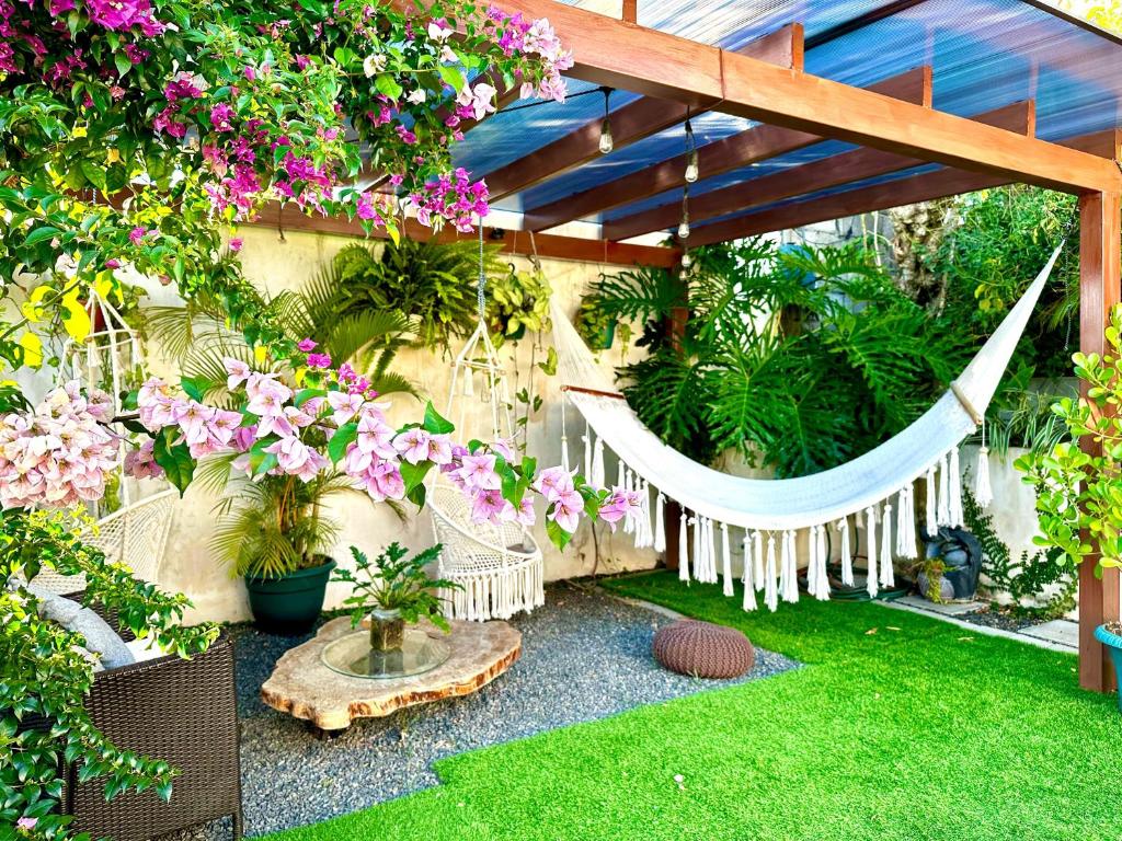 uma rede num jardim com flores e plantas em Airport Traveler's home. em Alajuela